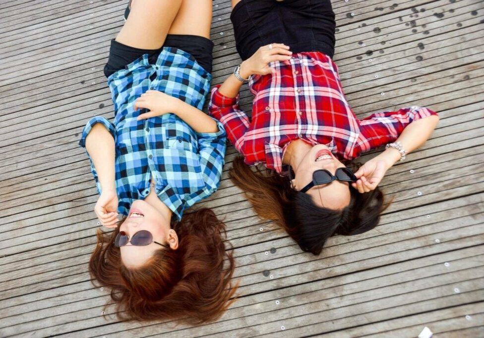 Two women laying on the ground wearing sunglasses.
